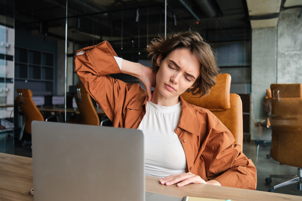 Woman feeling neck pain while working on laptop at office desk_ laptop stand