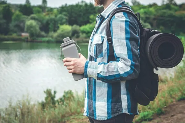 A man is holding his lightweight water bottle for travel