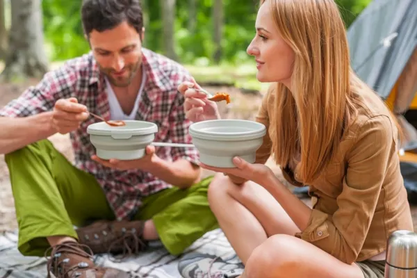 a couple are using camping bowl to eat meal