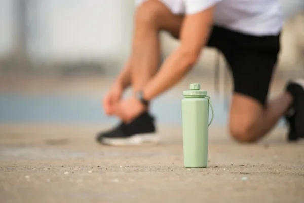A man is using a sports water bottle in gym