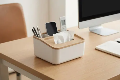 A multi-functional desk organizer tissue holder with integrated compartments holding pens, a remote control, and devices on a neat workspace.